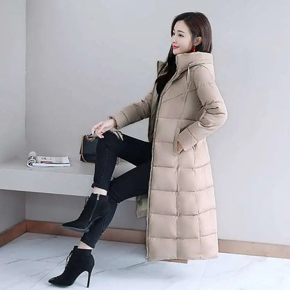 A woman wears a long, quilted beige down puffer coat with a high collar, zipper, and side pockets.