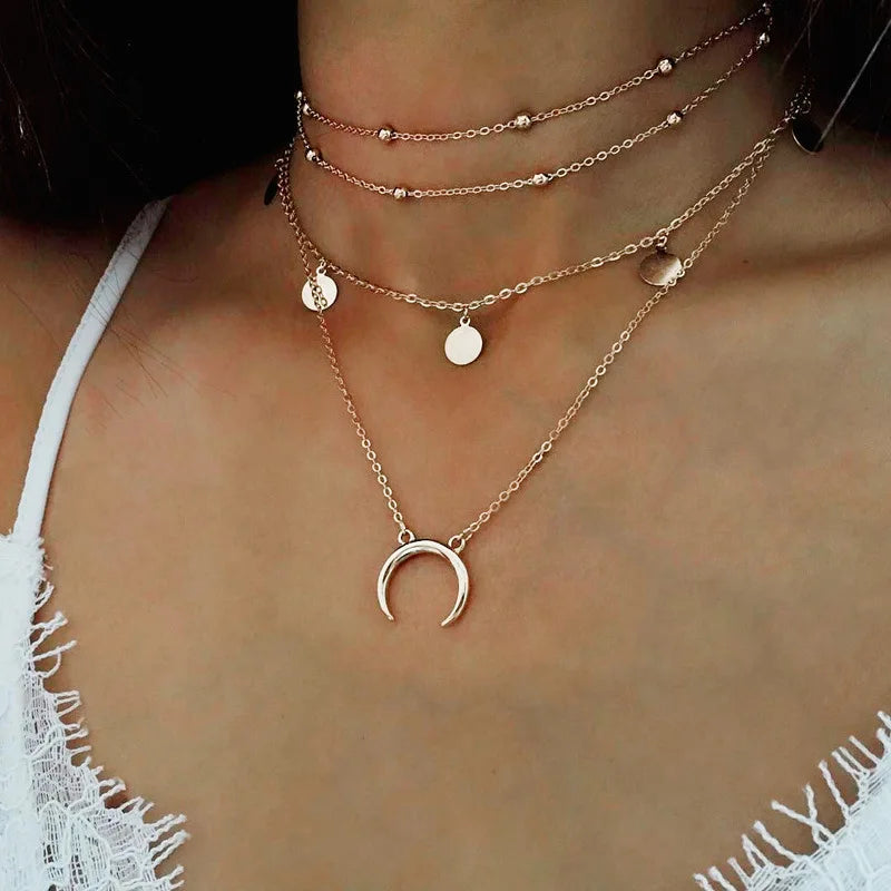 Gold-colored multilayer choker necklace featuring bead chains, coin charms, and a crescent moon pendant.