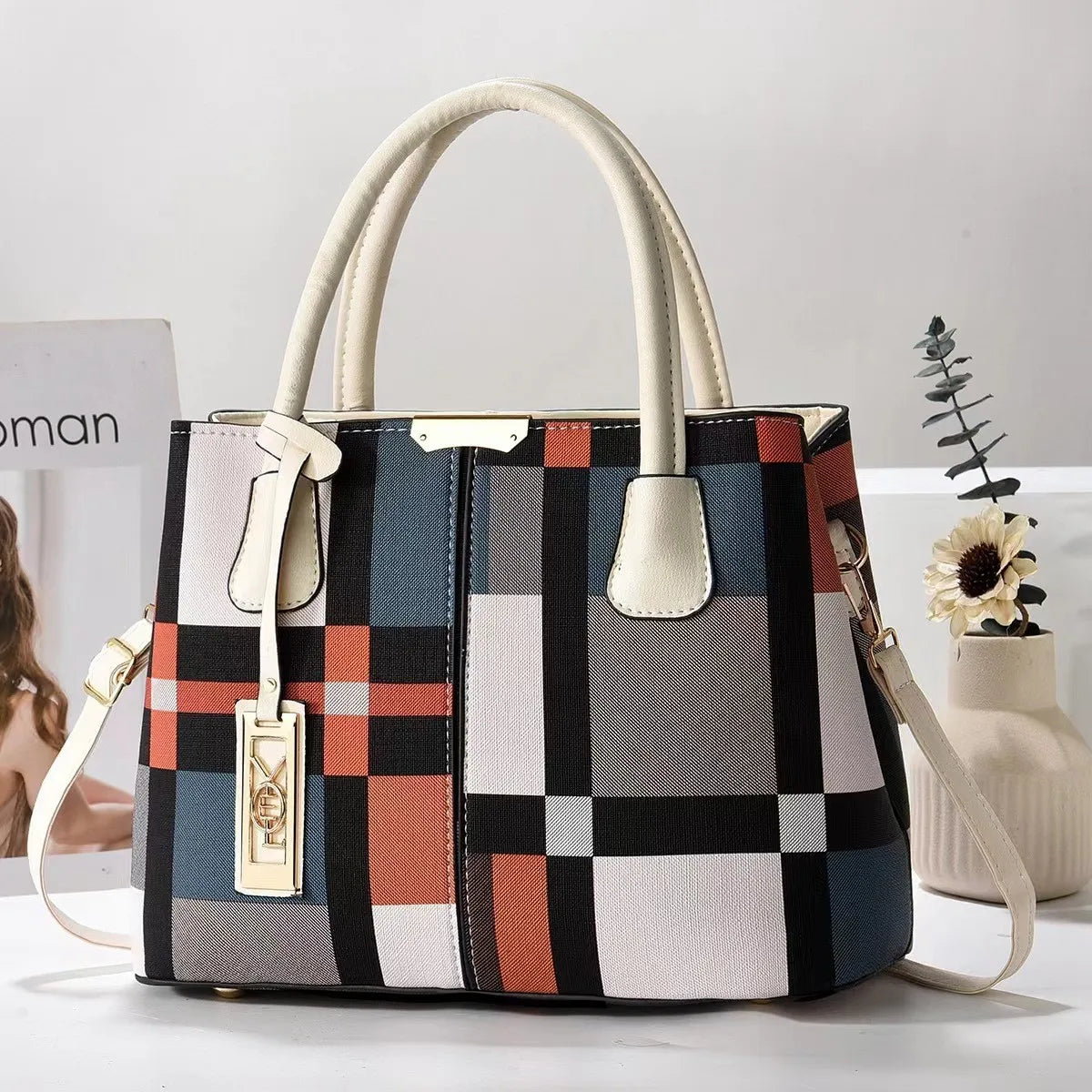 Multi-colored plaid structured tote bag with zip closure and adjustable strap for everyday use.