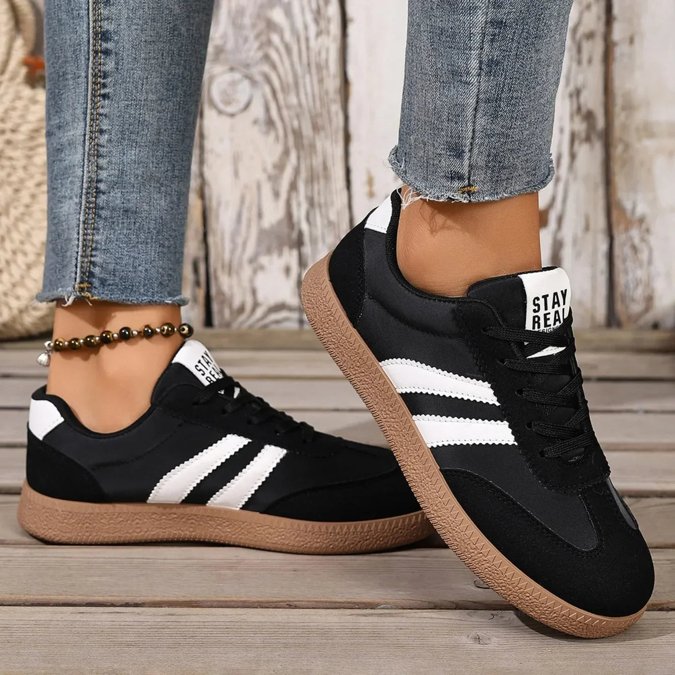 Black leather slip-on sneakers with white stripes and gum soles for casual daily wear.