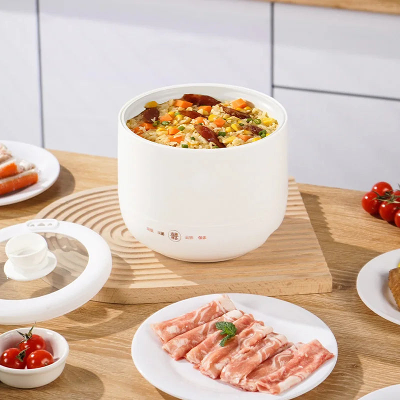 White multi-functional electric cooker filled with fried rice, placed on a wooden table with raw meat and vegetables.