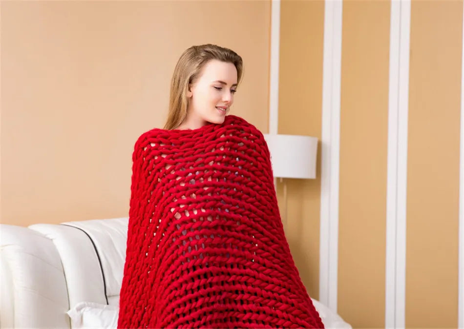 Red chunky hand-knitted blanket made from thick yarn roving, draped over shoulders.