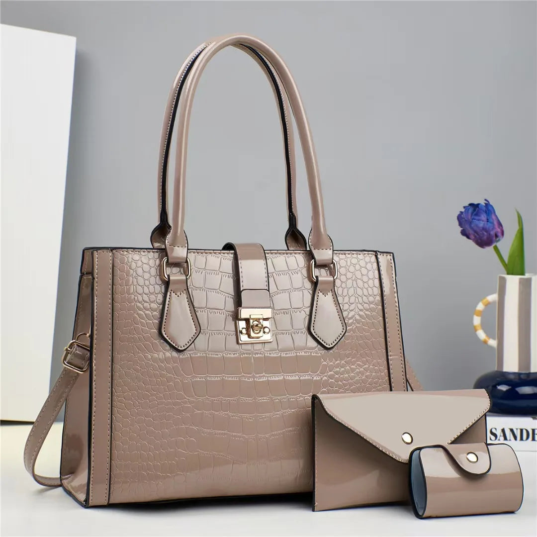 Taupe glossy patent leather crocodile-pattern handbag set with a structured tote, envelope clutch, and small wallet.