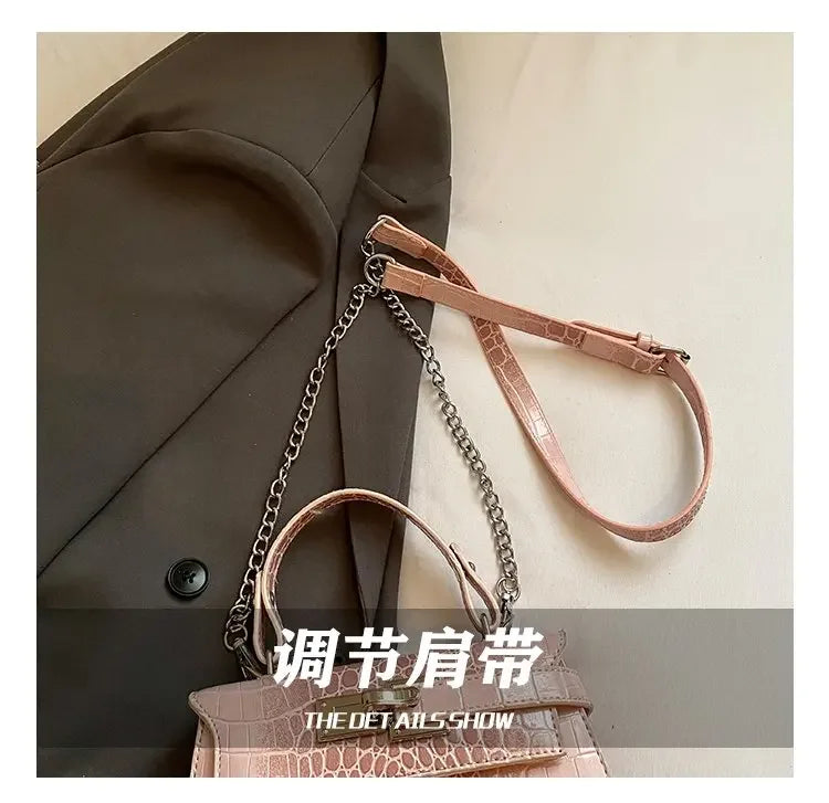 Pink faux leather crossbody bag with structured design, chain handle, and adjustable strap for baby essentials.
