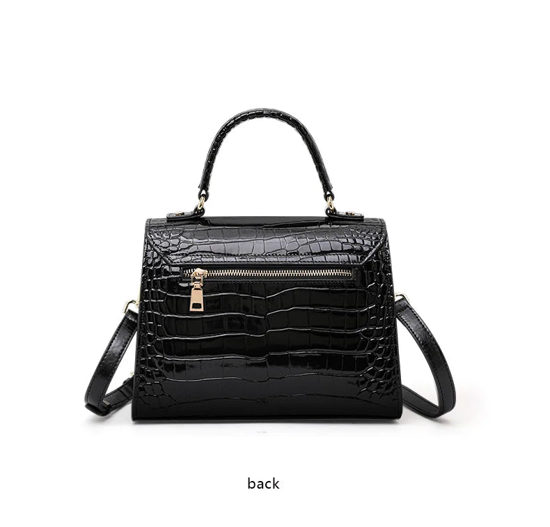 Black glossy leather crocodile-pattern handbag with top handle, zipper back pocket, and strap.