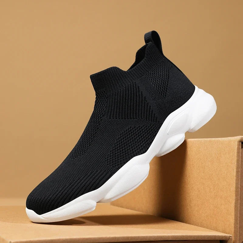 Black knit slip-on moccasin sneaker with white cushioned sole for breathable everyday casual wear.