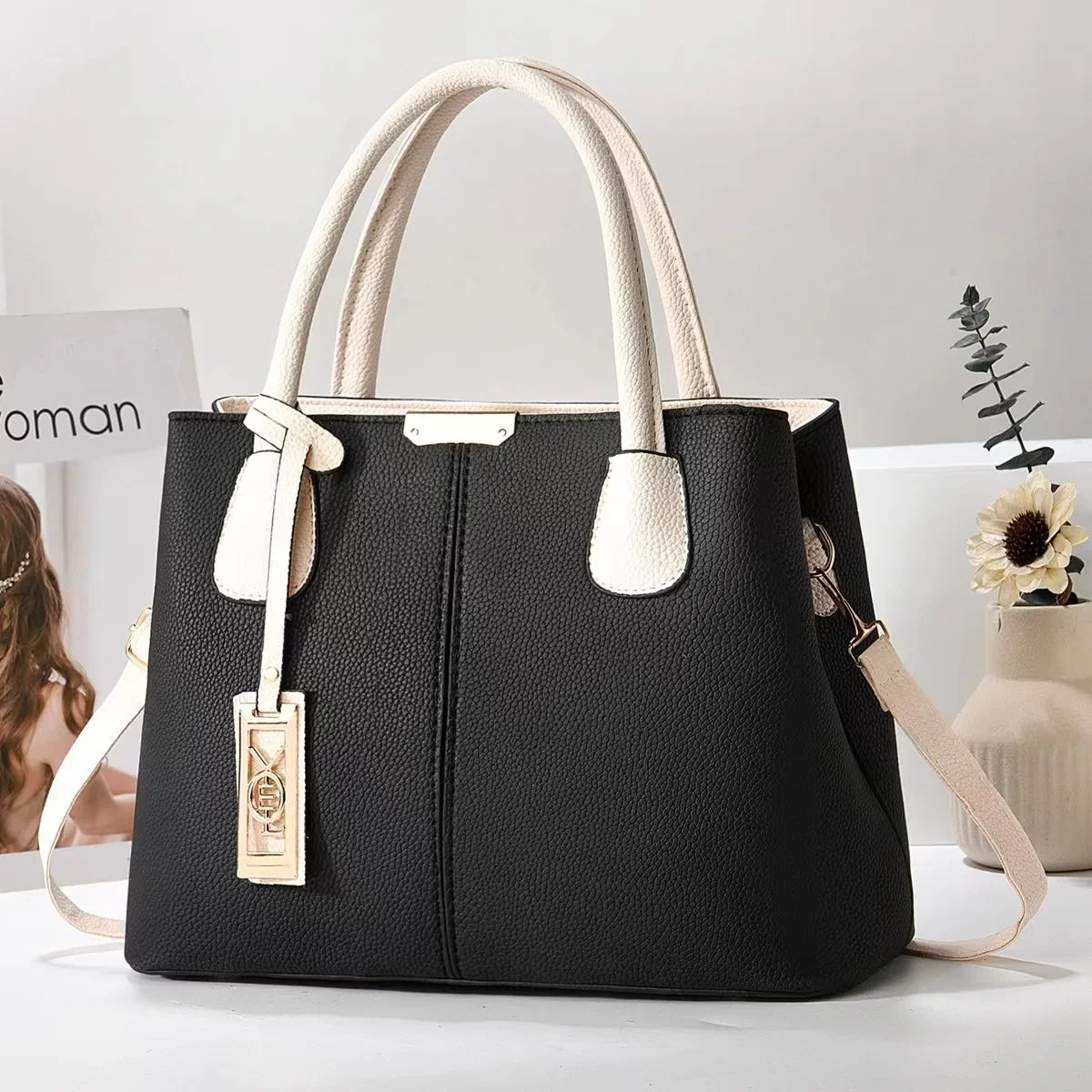 Black and white faux leather structured tote bag with a zip closure for everyday use.