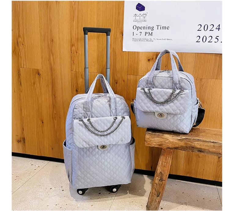 Light gray quilted nylon rolling backpack and matching handbag with chain accent on front pockets.