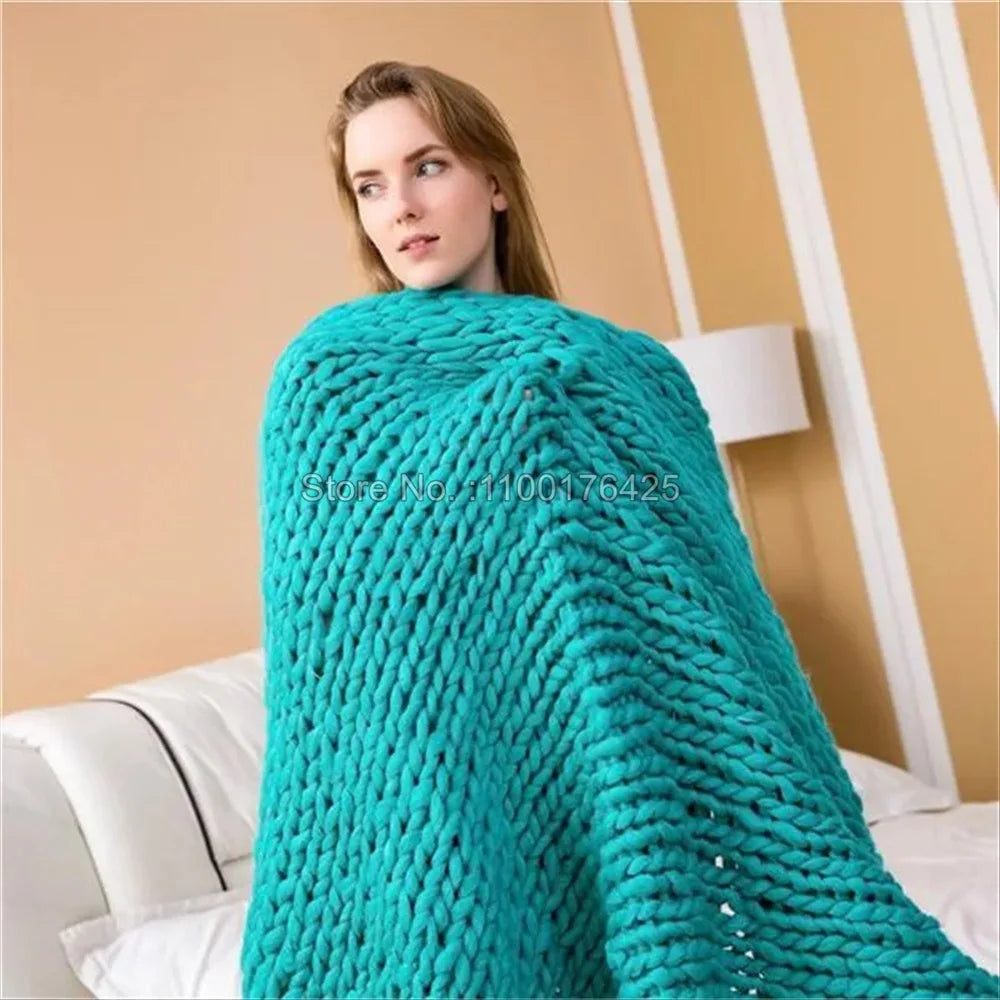 A woman wrapped in a chunky, turquoise hand-knitted roving yarn blanket.
