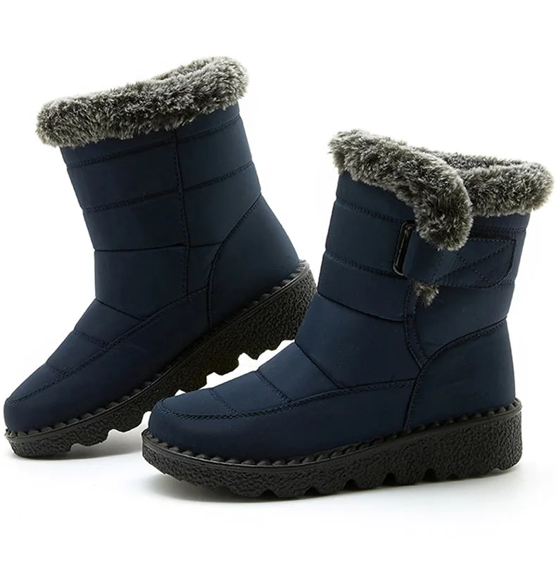 Navy blue waterproof snow boots with gray faux fur trim, quilted shaft, side strap, and thick black lug soles.