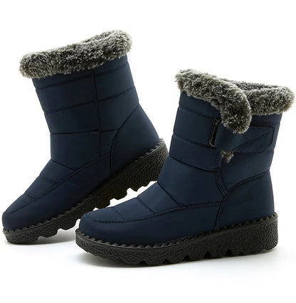 Navy blue waterproof snow boots with gray faux fur trim, quilted shaft, side strap, and thick black lug soles.