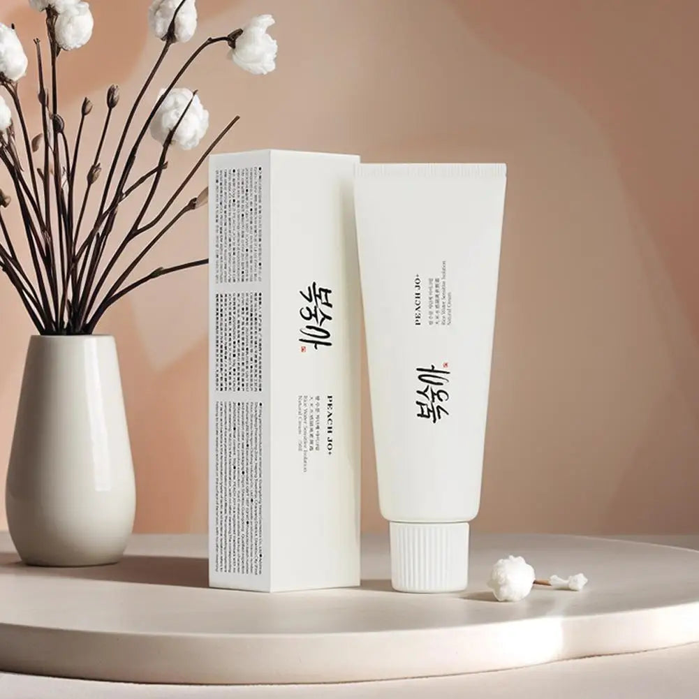 White SPF50+ rice extract moisturizing cream tube and box with black text, next to a vase of white flowers.