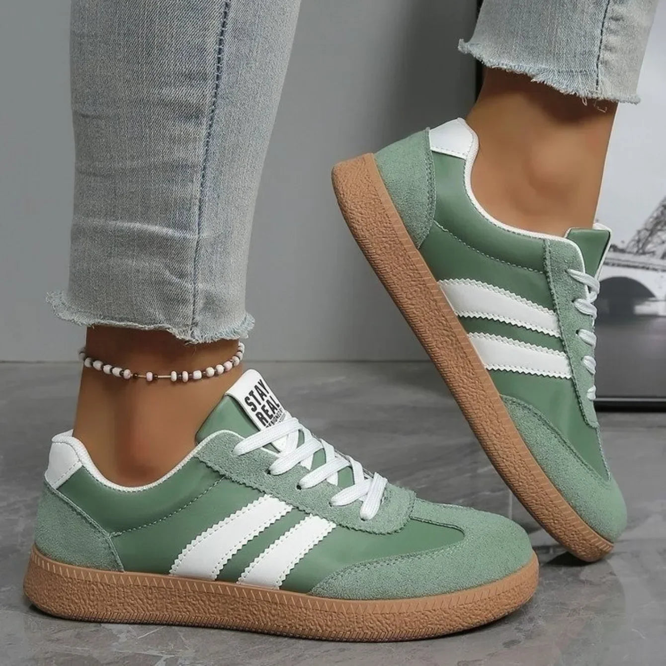 Sage green leather and suede slip-on sneakers with white stripes and gum soles for casual daily wear.