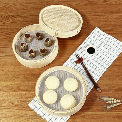 Two round bamboo steamer baskets with lids, containing dumplings and white buns, on a wooden table.