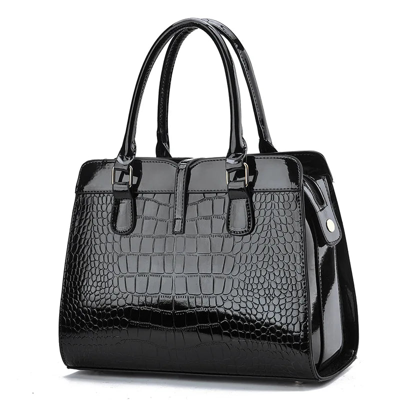 Black glossy crocodile-pattern leather handbag with dual top handles and structured tote design.