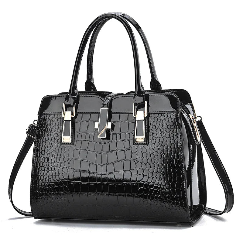 Black patent leather handbag with crocodile pattern, dual top handles, gold hardware accents, and a central clasp.