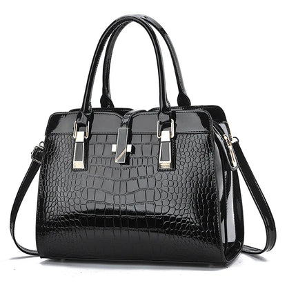 Black patent leather handbag with crocodile pattern, dual top handles, gold hardware accents, and a central clasp.