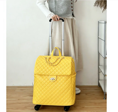 Bright yellow quilted faux-leather rolling suitcase with a gold-tone chain handle, top flap, and twist-lock closure.