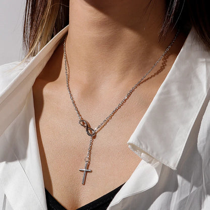 Silver-colored metal lariat necklace featuring an infinity loop connector and a hanging cross pendant.