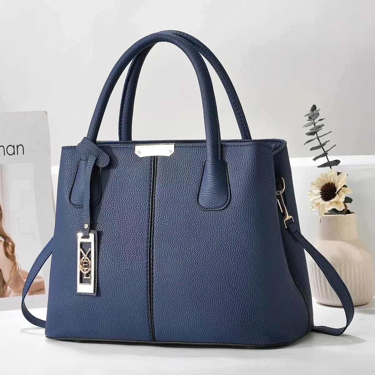 Navy blue faux leather structured tote bag with zip closure and adjustable strap for everyday use.