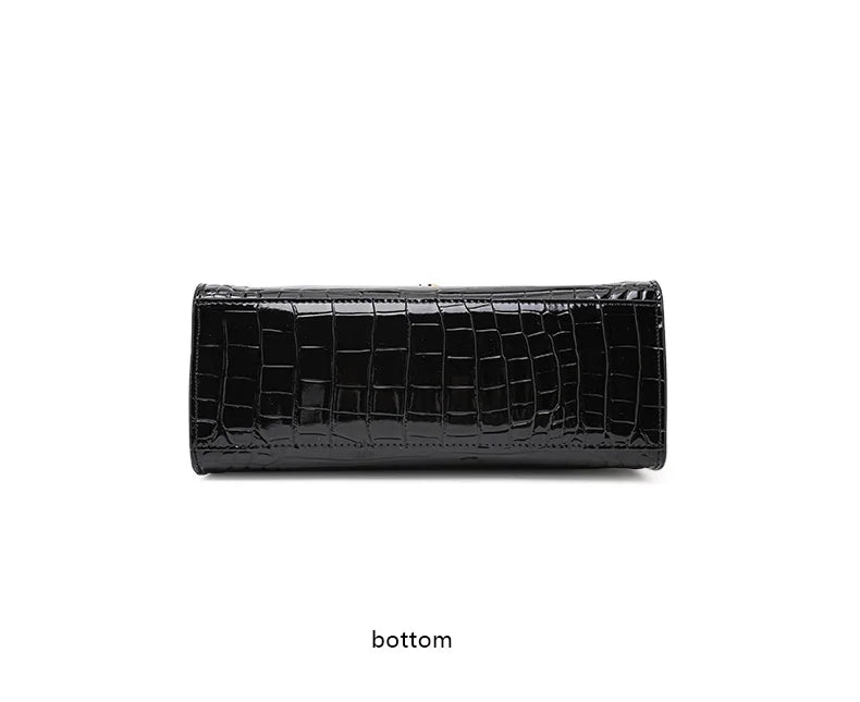 Black glossy cowhide handbag with a crocodile pattern, showing the flat bottom view.