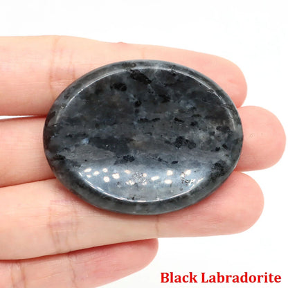 Polished oval black labradorite stone held in hand, used as home decor for meditation.