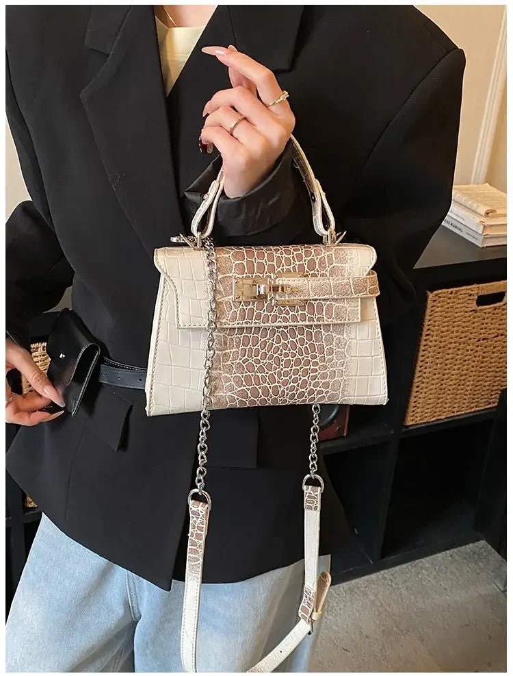 Off-white faux leather baby & kids diaper bag with crocodile texture, metal hardware, and an adjustable strap for parents.
