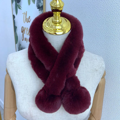 Burgundy plush faux fur cross scarf with two large pom-pom ends wrapped around a mannequin.