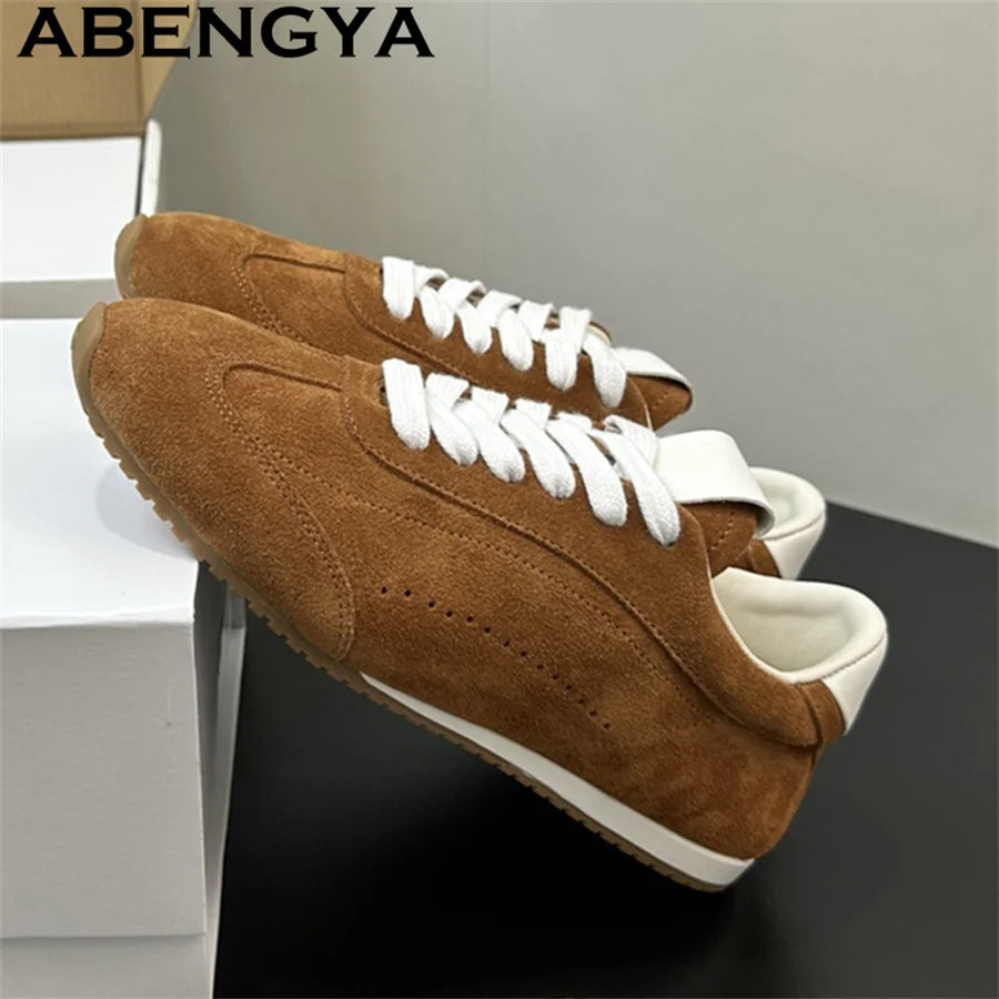 Brown suede lace-up sneakers with white laces, white trim, and flat rubber soles.