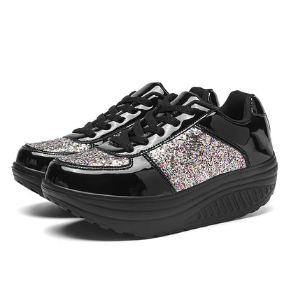 Black patent leather lace-up platform wedge sneakers with silver glitter side panels and chunky rocker soles.