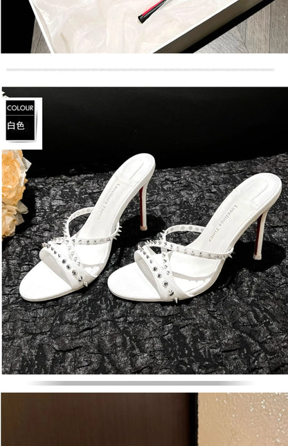 White open toe sandals with silver rivets and slim heels, a strappy design for evening wear.