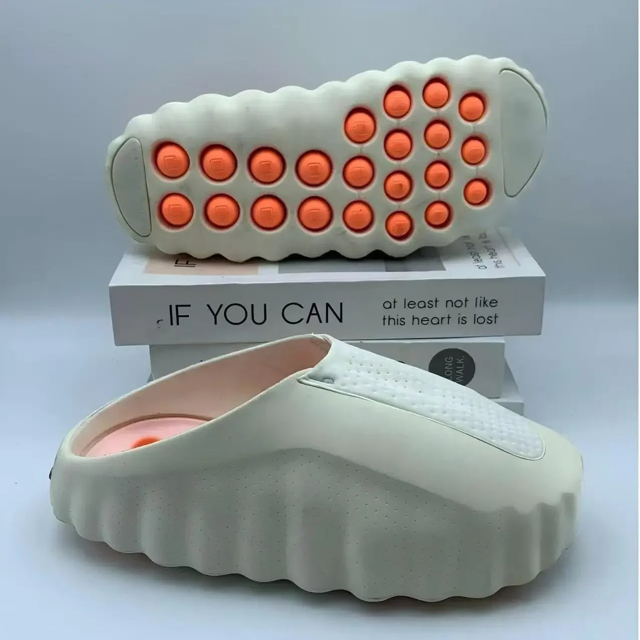 Off-white EVA slip-on sandals with orange massage nodules on the cushioned soles for indoor or outdoor wear.