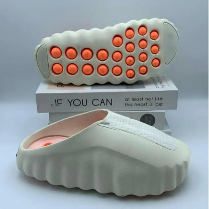 Off-white EVA slip-on sandals with orange massage nodules on the cushioned soles for indoor or outdoor wear.