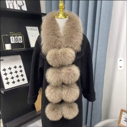 Brown faux fox fur scarf with four large pom-pom details, worn over a black coat.