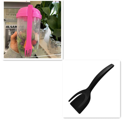 Clear salad cup with pink lid and attached pink fork holding salad, next to a separate black kitchen utensil.