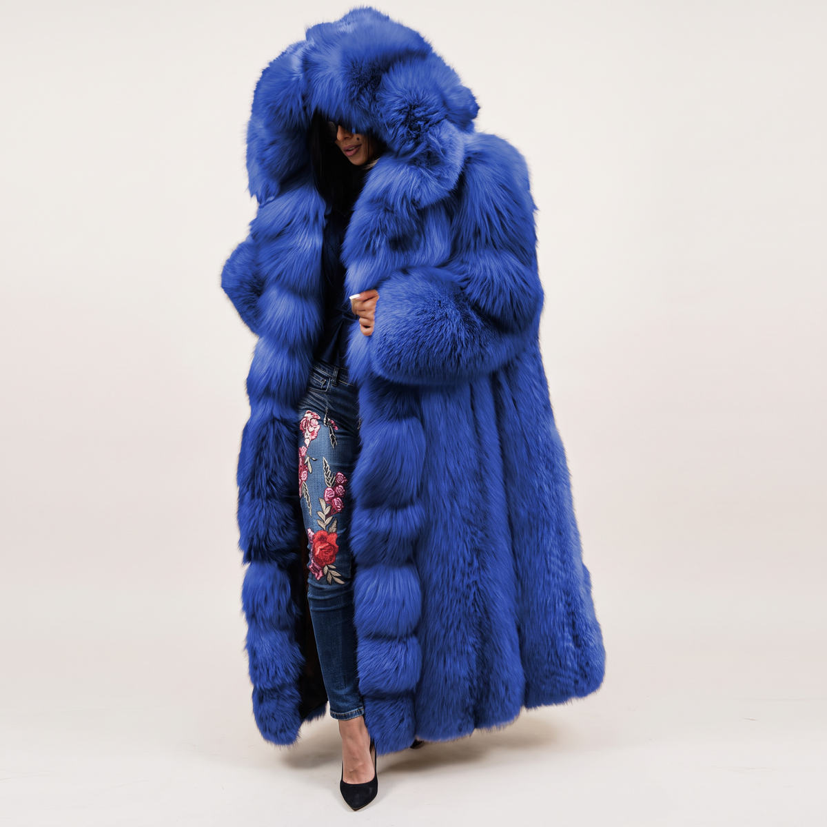 Royal blue faux fur hooded coat with an oversized collar, worn over floral embroidered jeans.