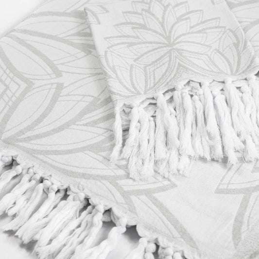 White patterned towel with a floral mandala design and knotted fringe trim.