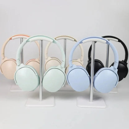 Five over-ear Bluetooth headphones in assorted colors displayed on separate metal stands.