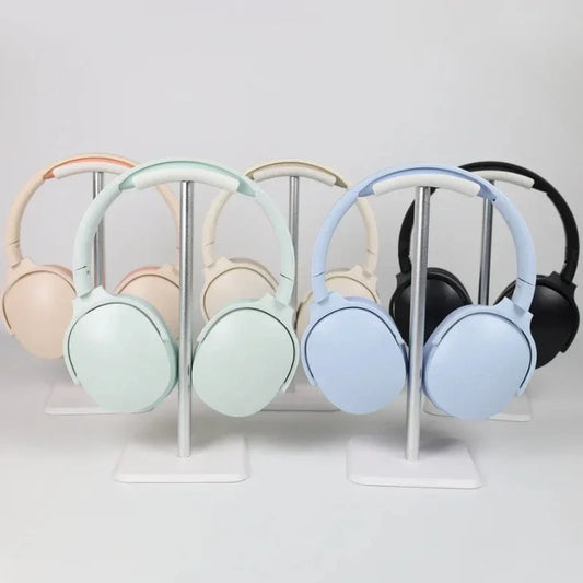 Five over-ear Bluetooth headphones in assorted colors displayed on separate metal stands.