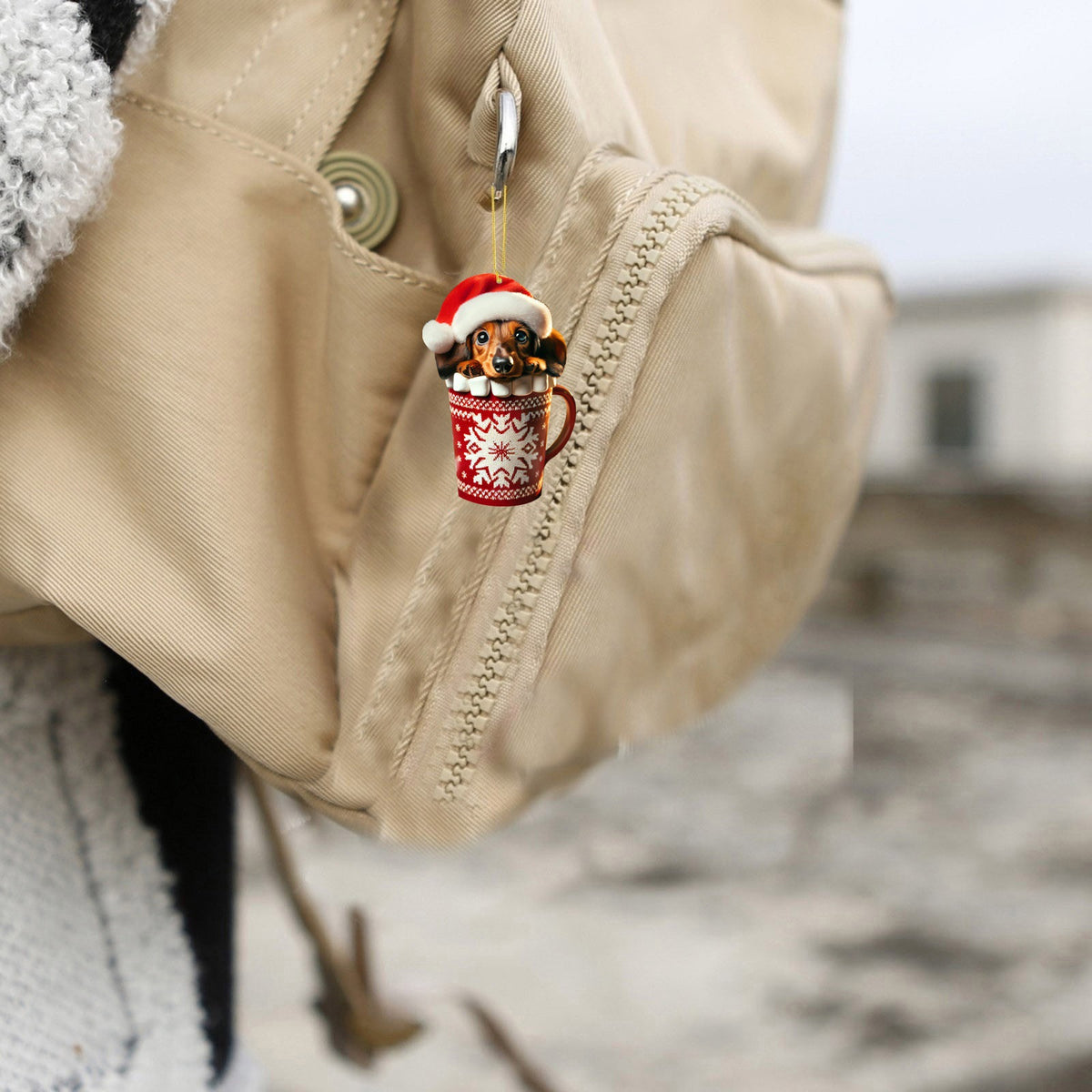 Dachshund in Santa hat ornament hanging from tan backpack