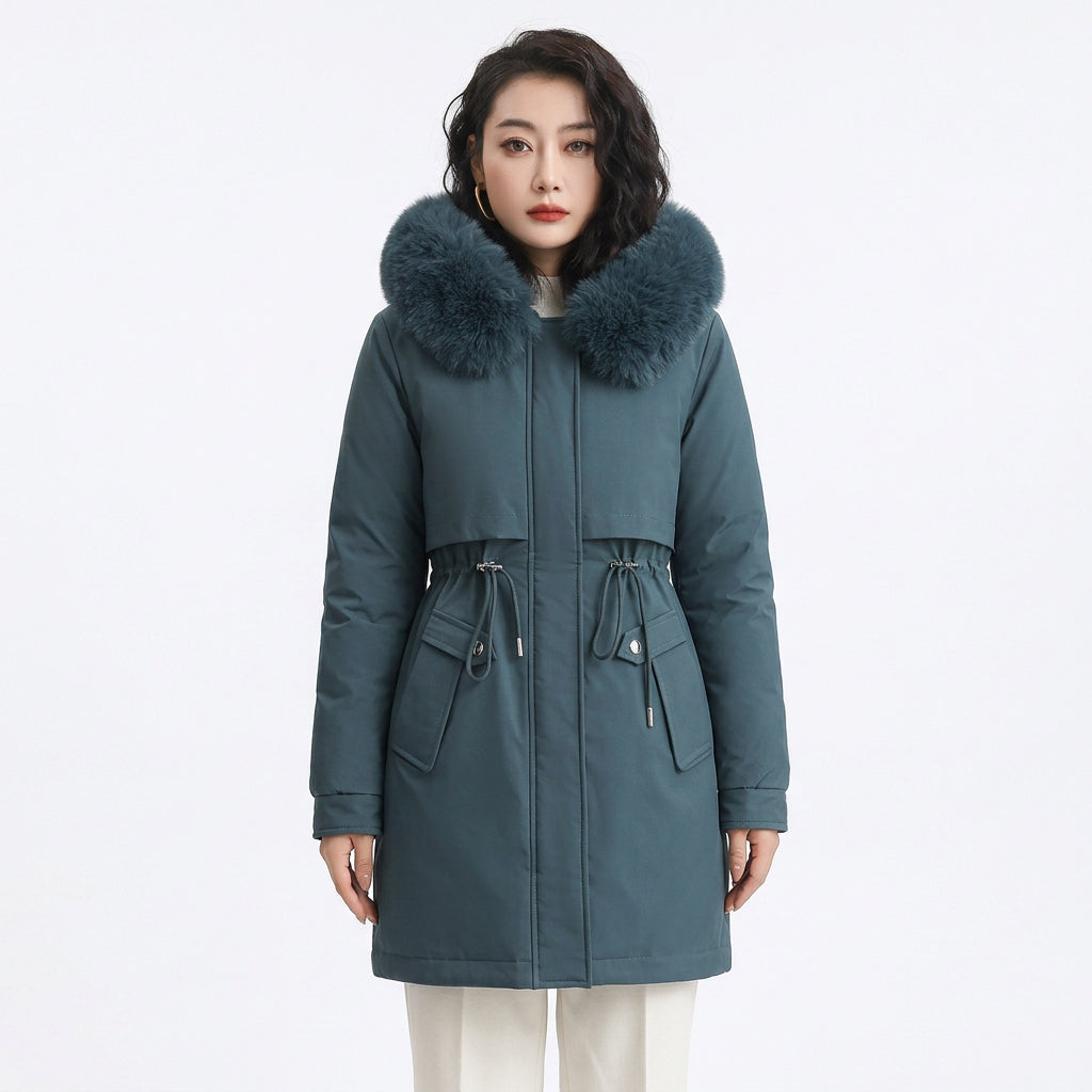 Woman wearing a fitted teal puffer coat featuring a large faux fur hood and drawstring waist.