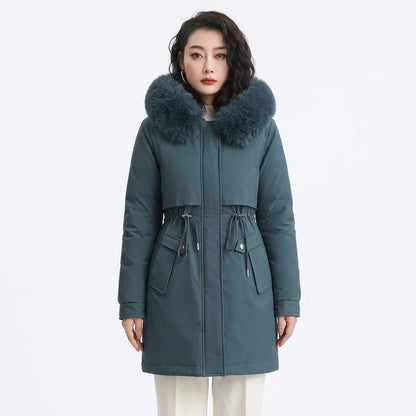 Woman wearing a fitted teal puffer coat featuring a large faux fur hood and drawstring waist.