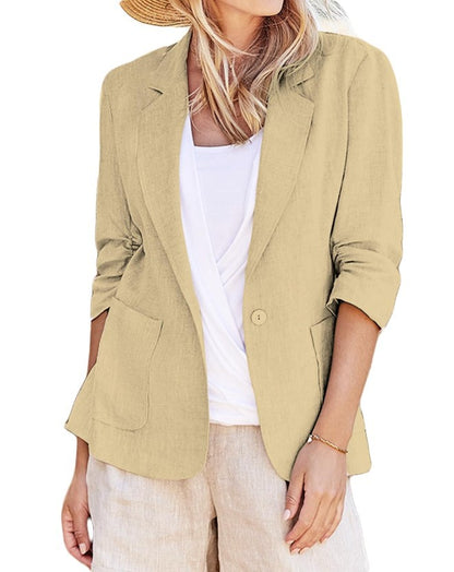 Woman wearing a beige single-breasted blazer with notched lapels and front patch pockets over a white top.