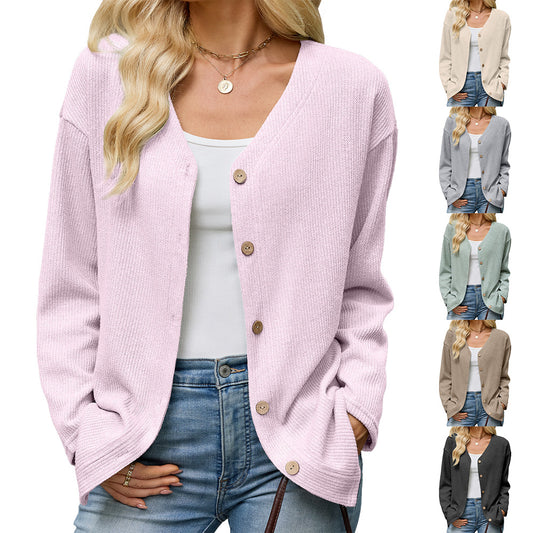 Woman wearing a light pink V-neck knit button cardigan over jeans and white top