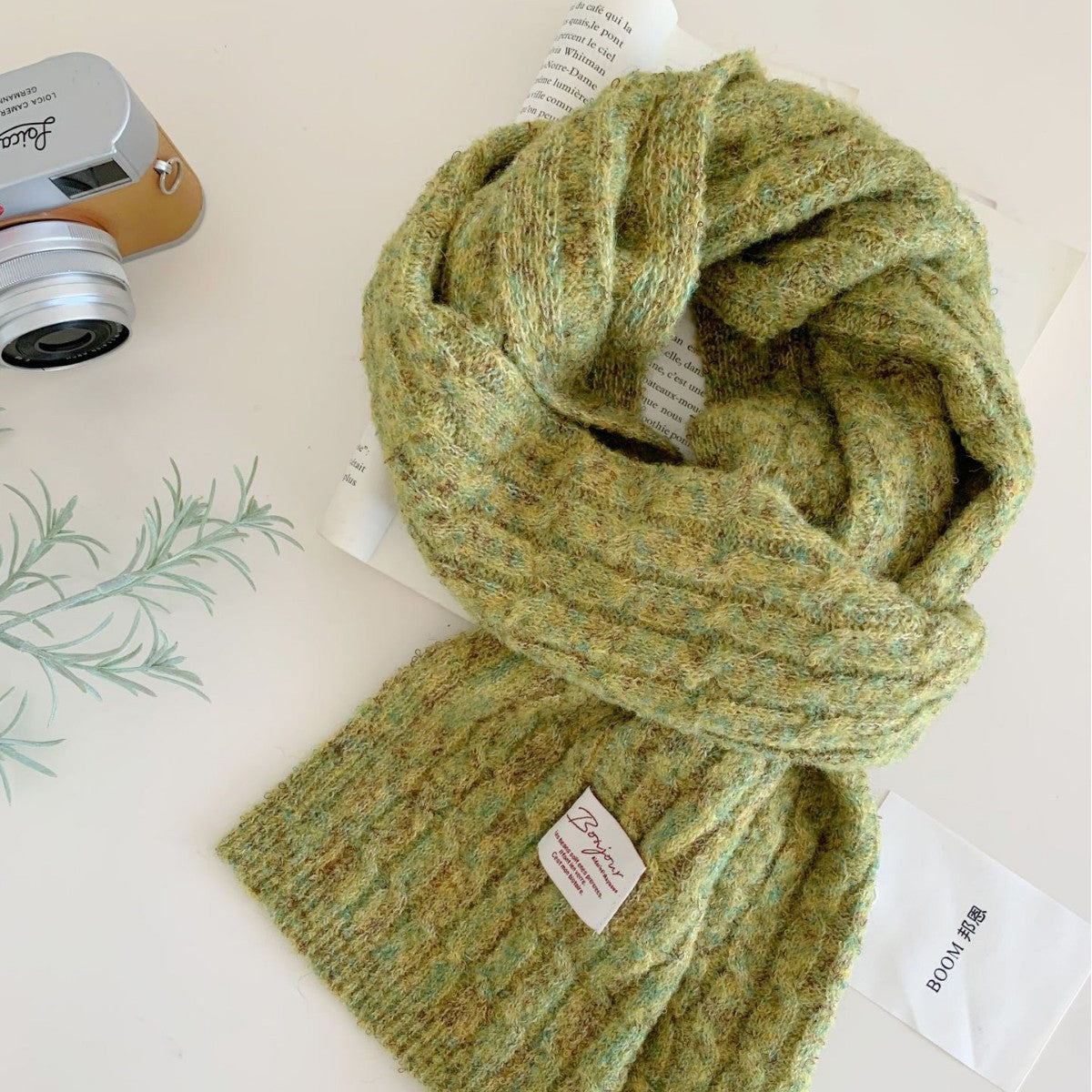 Green knit scarf with a small white label near the hem, laid flat.
