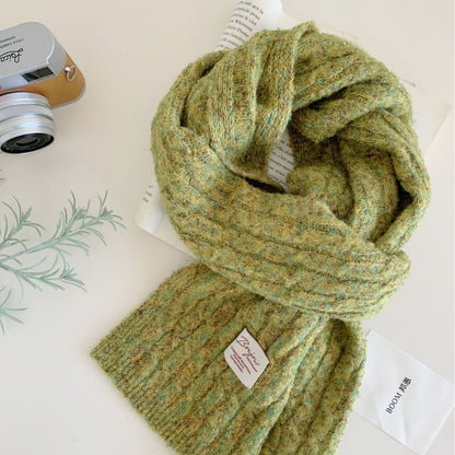 Green knit scarf with a small white label near the hem, laid flat.