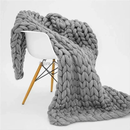 Chunky gray knit throw blanket draped over a white mid-century modern chair