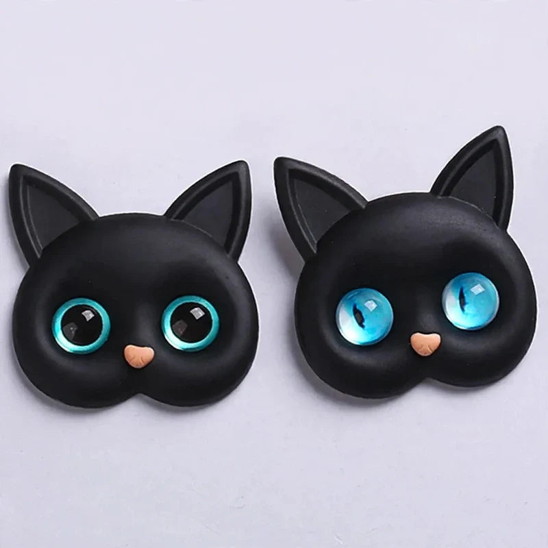 Two black cat head phone grips featuring pointed ears and large blue eyes on a light background