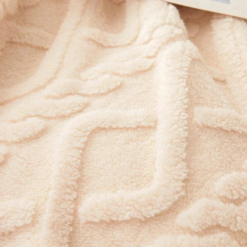 Close-up of a soft beige fleece blanket with a raised textured geometric pattern.