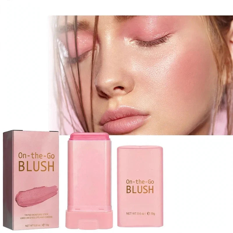 Pink cream blush stick with matching box and closed cap next to a model wearing pink blush on cheeks and eyelids.